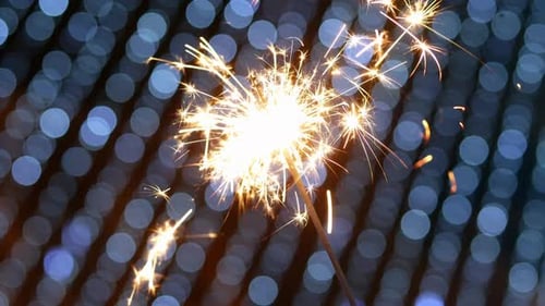 Close-up of Firework Sparkler Burning with Blue Bokeh Lights From Garland