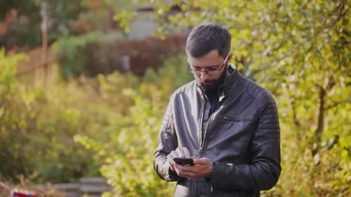 Young Bearded Man Using Phone in Sunny Park