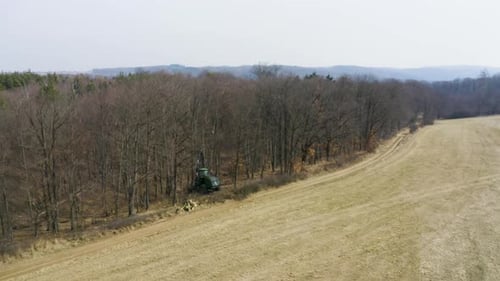 Forst-Erntemaschine am Rande eines toten, blattlosen Waldes, Drohnenschuss
