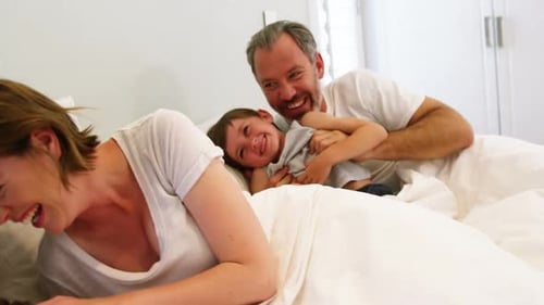 Family Laughing and Playing Together on Bed