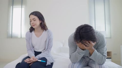 Ein junges asiatisches Paar fühlt sich nach einem positiven Schwangerschaftstest schockiert und möchte nicht schwanger werden.