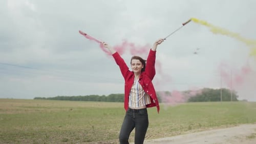 Woman Holding Smoke Flares in a Grassy Field