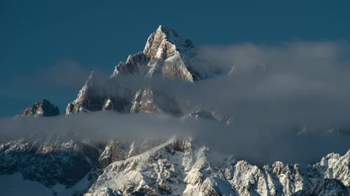 Snowy Mountains and Clouds Against Blue Sky