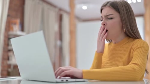 Sleepy Young Woman Yawning in Office