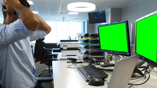 Stressed Man Rubbing Temples at Green Screen Monitors