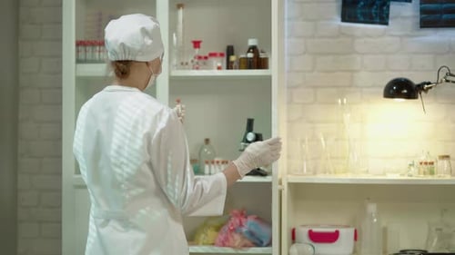 Scientist Selects Vial from Brightly Lit Medical Cabinet