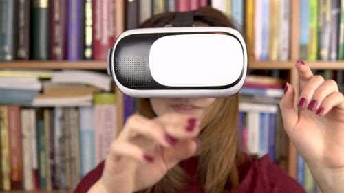 Young Woman in VR Glasses in the Library. A Woman with a VR Helmet on Her Head Examines and Touches