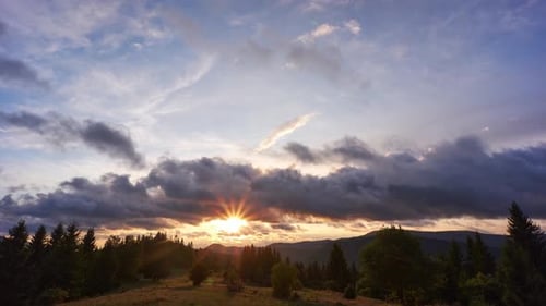 Les nuages se déplacent rapidement sur le paysage forestier au coucher du soleil