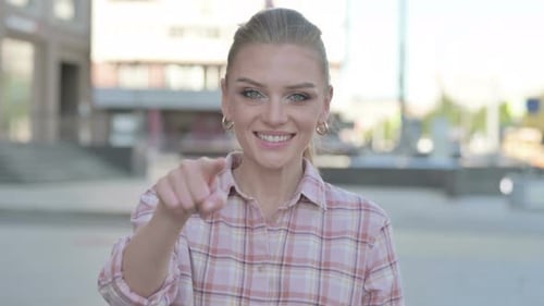 Smiling Blonde Woman Points Finger at the Viewer