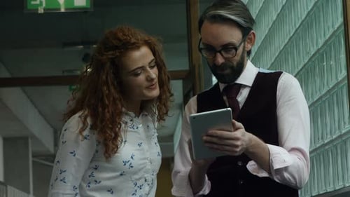 Man and Woman Discuss Tablet in Office