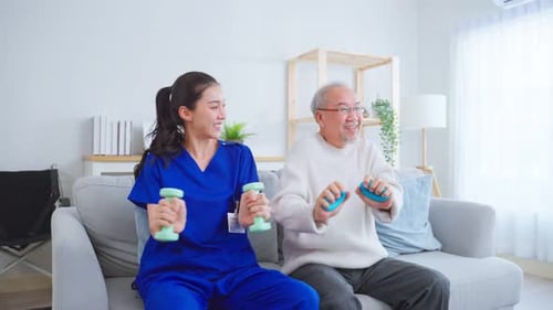 Asian senior funny man doing physical therapy with support from nurse at nursing home.