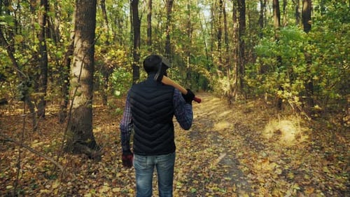 A Man Walks in the Autumn Woods with an Ax