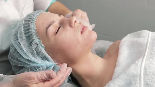 Woman Lying on Bed Having Face Cleansed