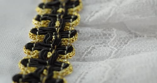 Weiße Spitze mit schwarzem und goldenem Dekor in Nahaufnahme