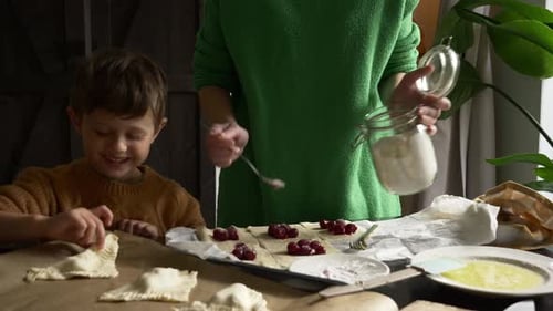 Child and Adult Baking Cherry Pastries Together at Home