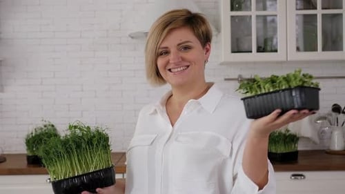 Primer plano de una mujer joven que sostiene macetas de microvegetación con guisantes germinados