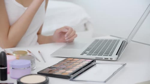 Manos de mujer con aprendizaje de maquillaje con pincel en la mejilla en computadora portátil con curso tutorial.