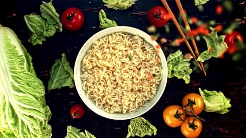 Vegetables Being Added to Bowl of Ramen Noodles