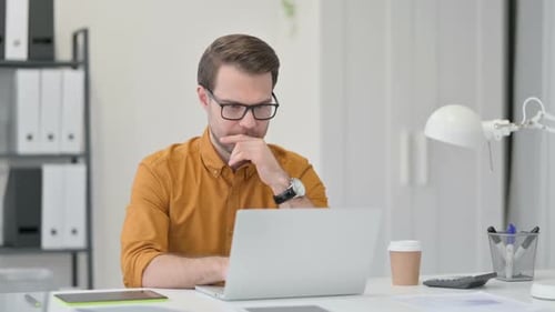 Junger Mann mit Laptop trinkt Kaffee im Büro