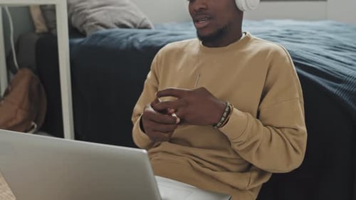 Young Man with Headphones Talking on Laptop