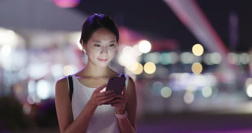 Woman use of mobile phone in city at night