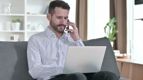 Adult Working on Laptop and Talking on Phone