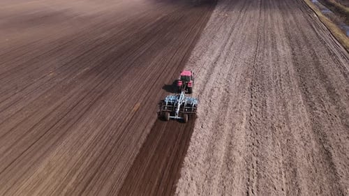 Tractor Plows Ground on Cultivated Farm Field