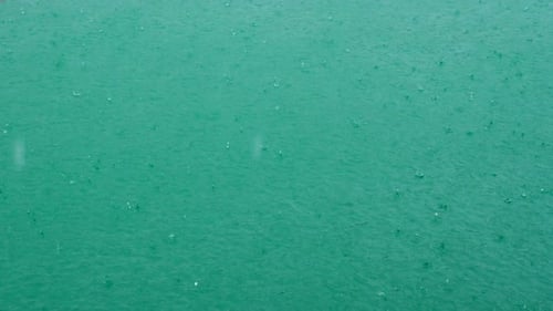 Regen fällt am türkisfarbenen See am Sommertag Regentropfen fallen auf Flusswasser