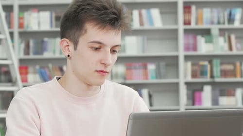 Photo recadrée d'un jeune étudiant souriant à la caméra à la bibliothèque