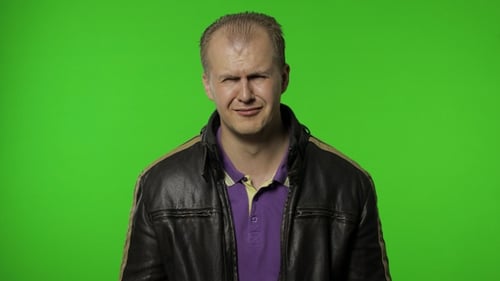 Upset Man Rubs Eyes on Green Background