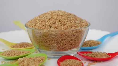 Rotating view of sesame seeds filled in glass bowl and plastic spoons