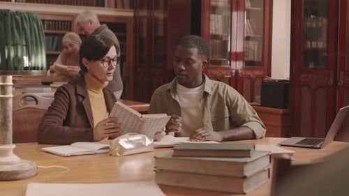 Professor Assisting Student with Studies at Library