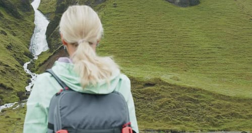 Woman Tourist with Backpack in Front of Icelandic Waterfall Near Fjadrargljufur at South Coast of