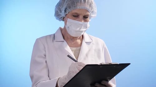 Woman in Mask Writing on Clipboard in Hospital