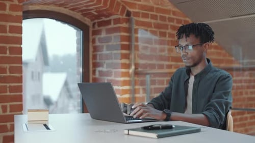 African American Man Smiling at Camera while Working at Office Desk