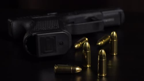 Nahaufnahme von Kugeln und einer Waffe auf einem schwarzen Tisch