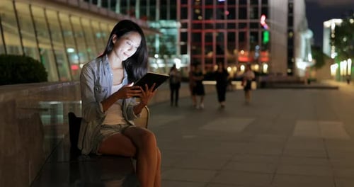 Woman Using Tablet at Night in City