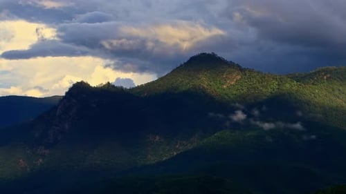 Timelapse Clouds Swirl Over a Green Mountain Valley