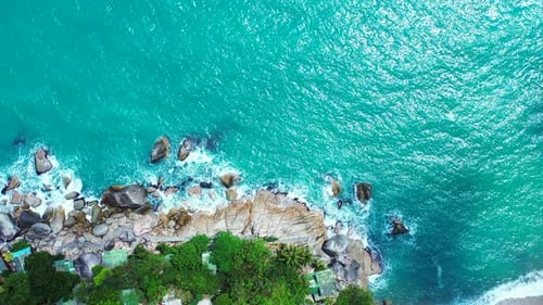 Beautiful seaside of tropical island with rocky coastline splashed by white ocean waves on turquoise