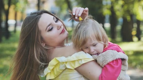 A Mother Hugs Her Young Daughter in the Park in the Summer