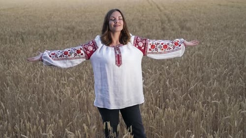 Happy Ukrainian Woman with Open Arms in Yellow Ripe Wheat Field