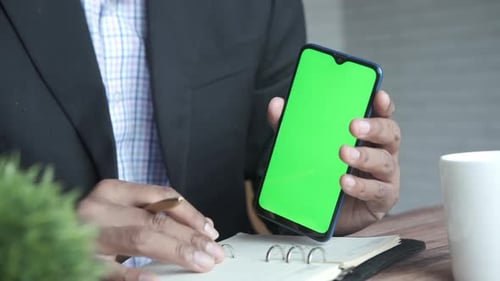 Nahaufnahme eines jungen Mannes mit Smartphone mit grünem Bildschirm