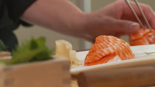 Preparing Sliced Salmon with Chopsticks on Plate
