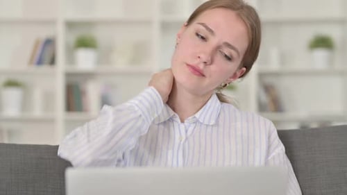Woman Massaging Stiff Neck While Using Laptop