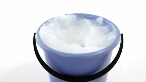 Cleaning sponge falling in to bucket of soap suds