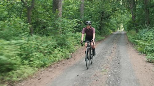 Gravel cycling. Woman riding road bicycle in forest.
