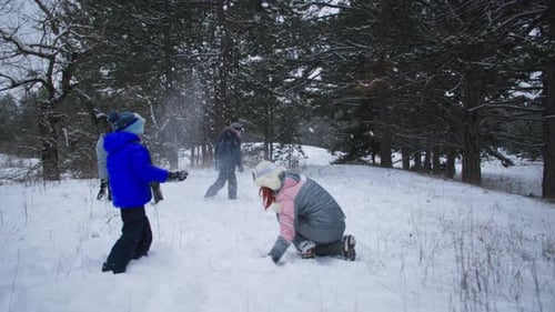 Family Having a Winter Snowball Fight in Forest