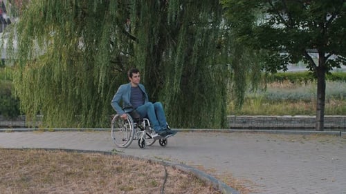 Man in Wheelchair Driving Down the Street