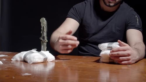 Man Counts Money near Packets at Wooden Table