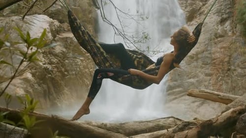 Girl Relaxes in Hammock at Close Bright Waterfall